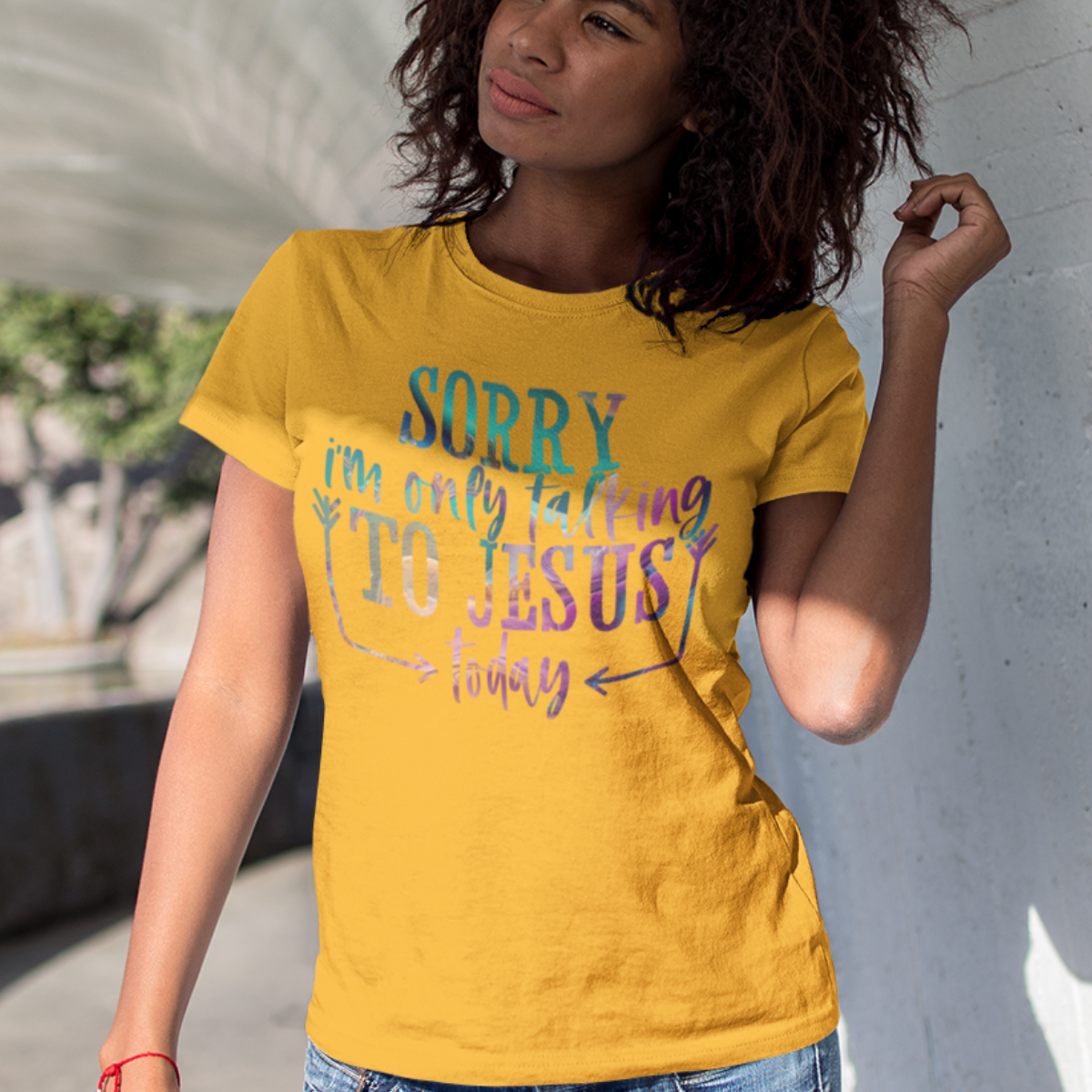 Woman wearing a gold t-shirt with multicolor text 'SORRY i'm only talking TO JESUS today'.