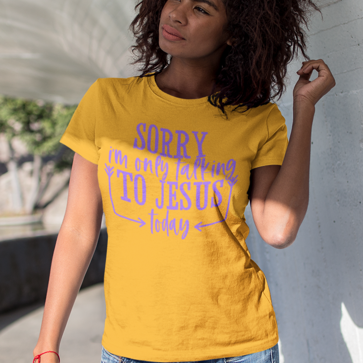 Woman wearing a gold t-shirt with purple text 'SORRY i'm only talking TO JESUS today'.