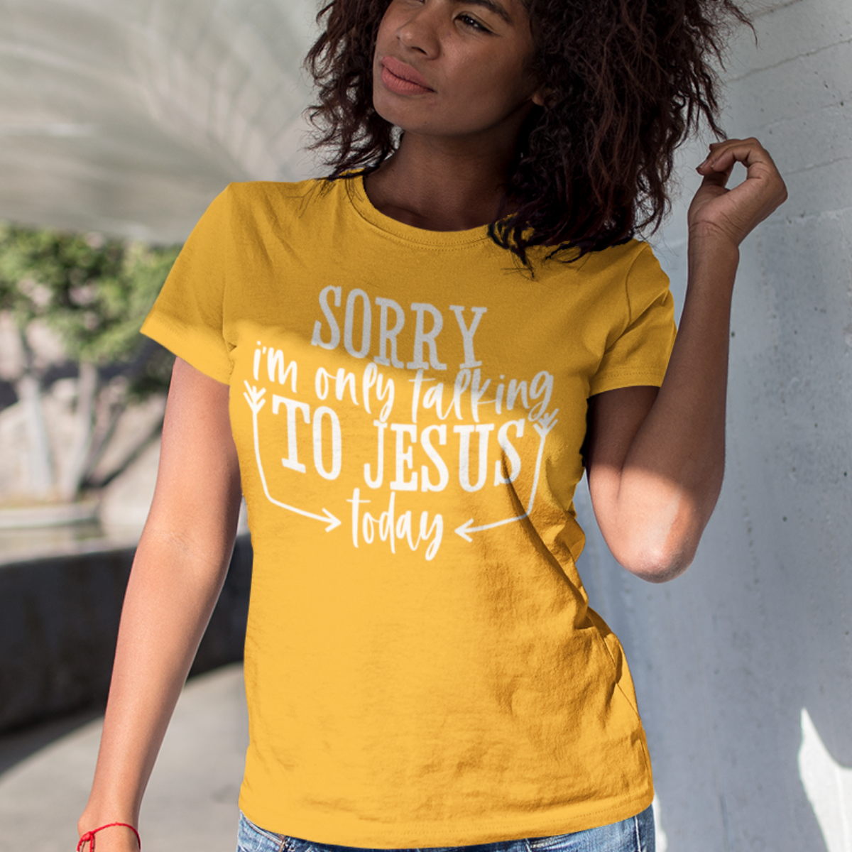 Woman wearing a gold t-shirt with white text 'SORRY i'm only talking TO JESUS today'.