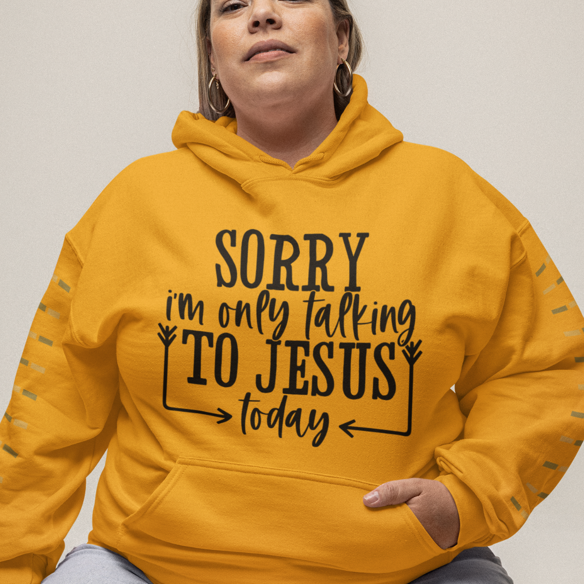 Woman wearing a gold hoodie with black text 'SORRY i'm only talking TO JESUS today'.