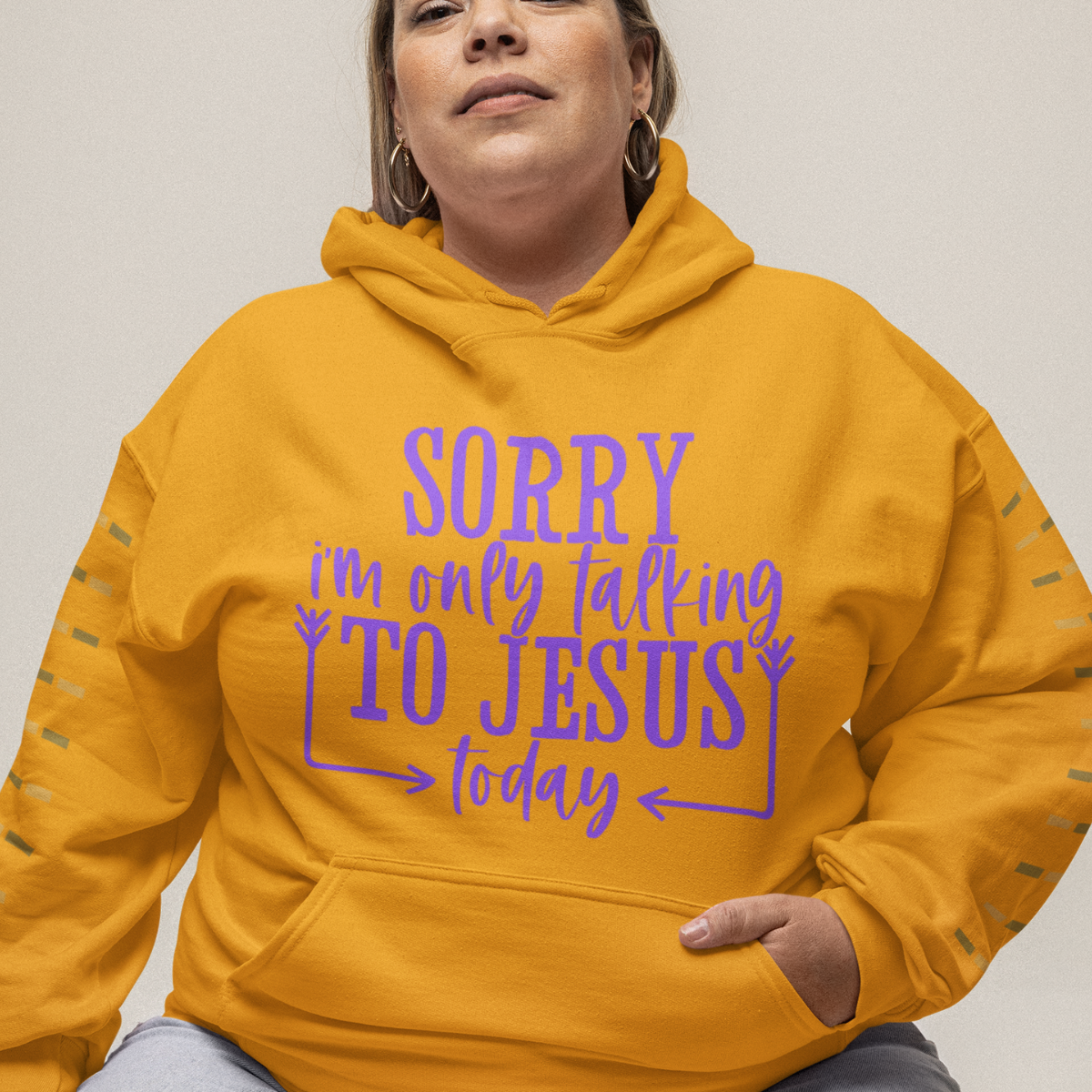 Woman wearing a gold hoodie with purple text 'SORRY i'm only talking TO JESUS today'.