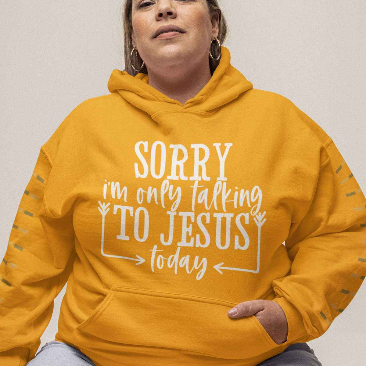 Woman wearing a gold hoodie with white text 'SORRY i'm only talking TO JESUS today'.