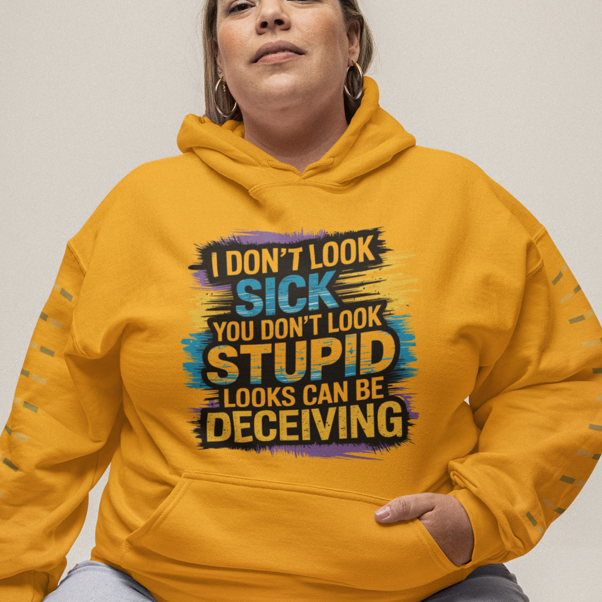 Woman wearing a gold lupus awareness hoodie with bold text 'I Don’t Look Sick, You Don’t Look Stupid, Looks Can Be Deceiving'.