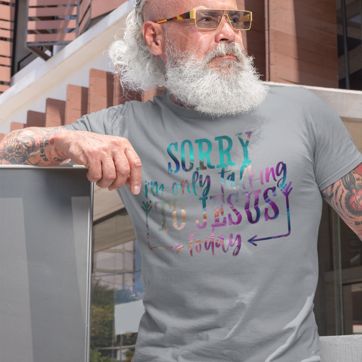 Man wearing a gray t-shirt with multicolor text 'SORRY i'm only talking TO JESUS today' outdoors.