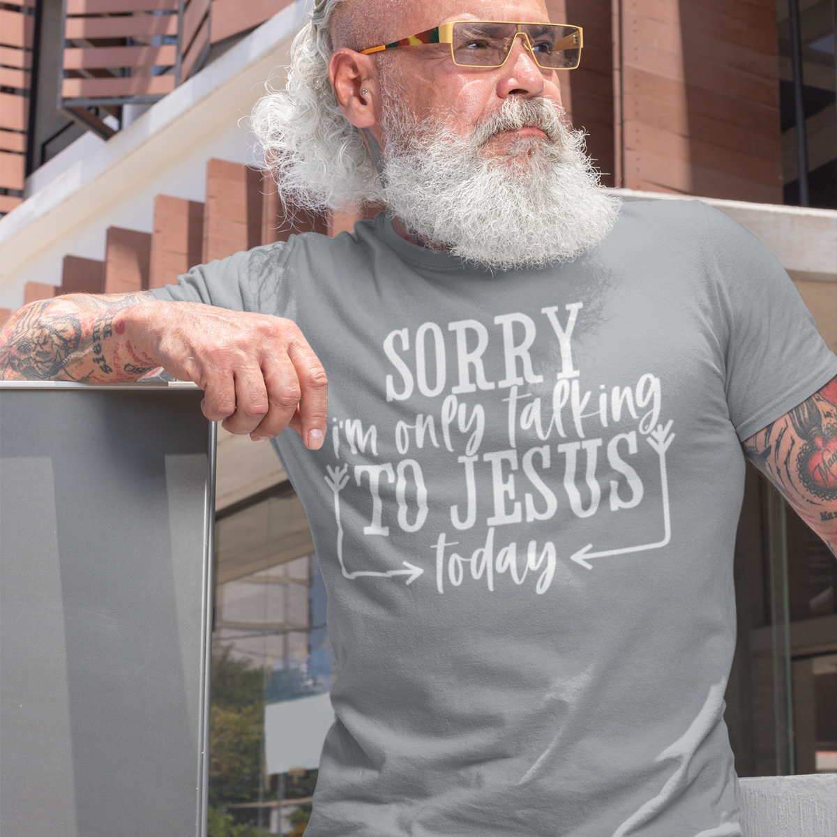 Man wearing a gray t-shirt with white text 'SORRY i'm only talking TO JESUS today' outdoors.