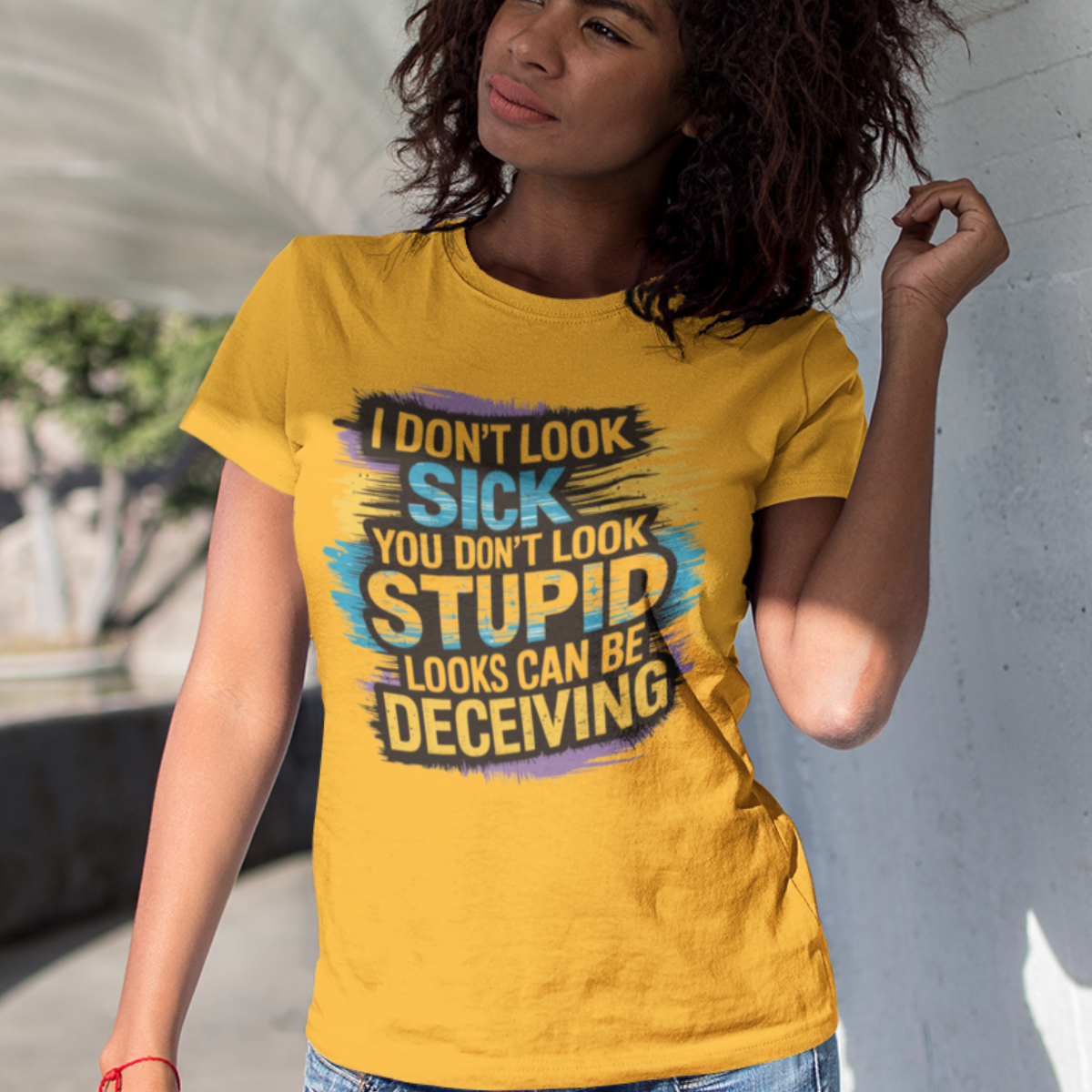 Woman wearing a gold lupus awareness tee with bold text 'I Don’t Look Sick, You Don’t Look Stupid, Looks Can Be Deceiving'.