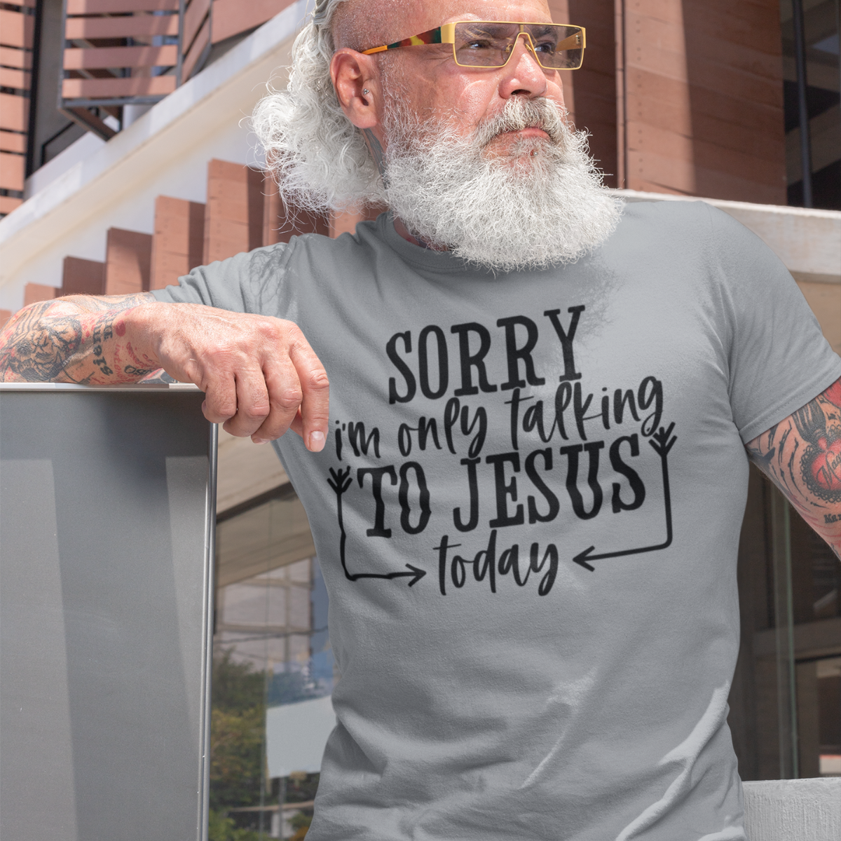 Man wearing a gray t-shirt with black text 'SORRY i'm only talking TO JESUS today' outdoors.
